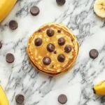 Top-down view of delicious banana chocolate chip pancakes on a marble surface