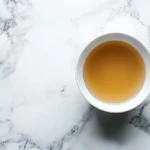 A bowl of bone broth on a marble surface.