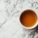 A warm mug of bone broth on a marble surface.